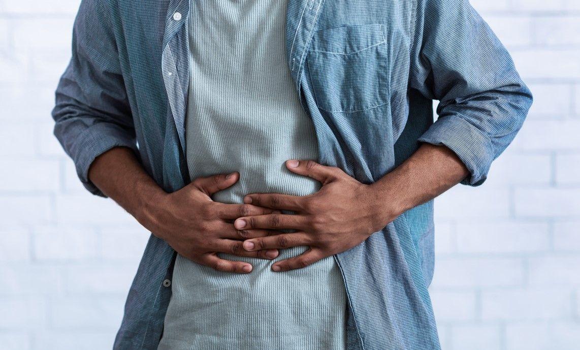 Man stood up holding his stomach in discomfort