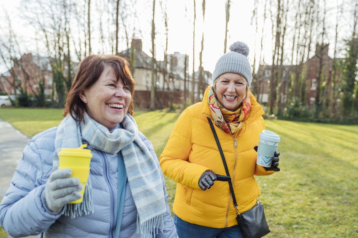 Female friends enjoying a winter walk with a hot drink