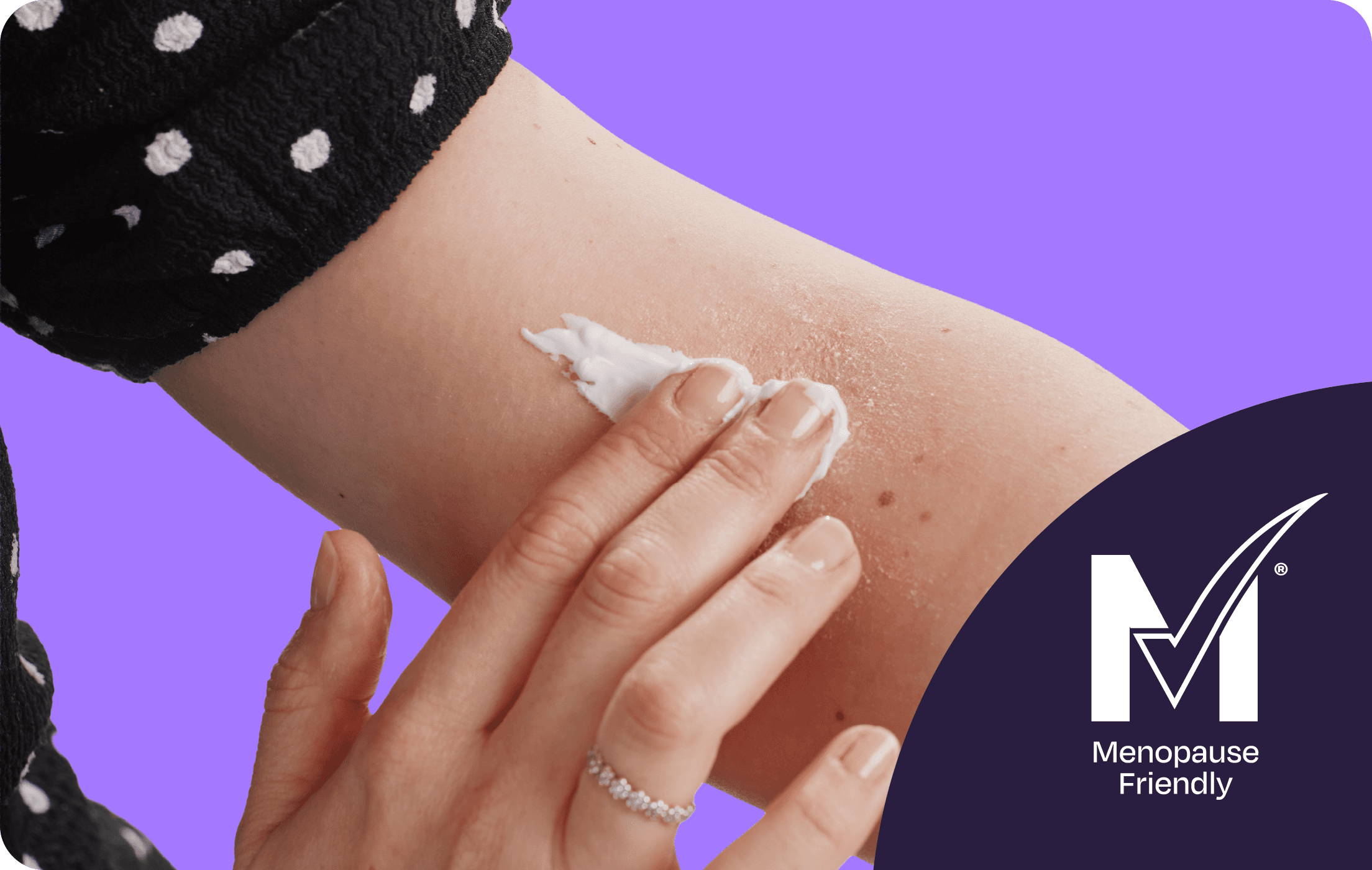 A person applies cream to a dry, red patch on their arm, with a polka-dot sleeve visible, against a purple background. "Menopause Friendly" logo in corner.