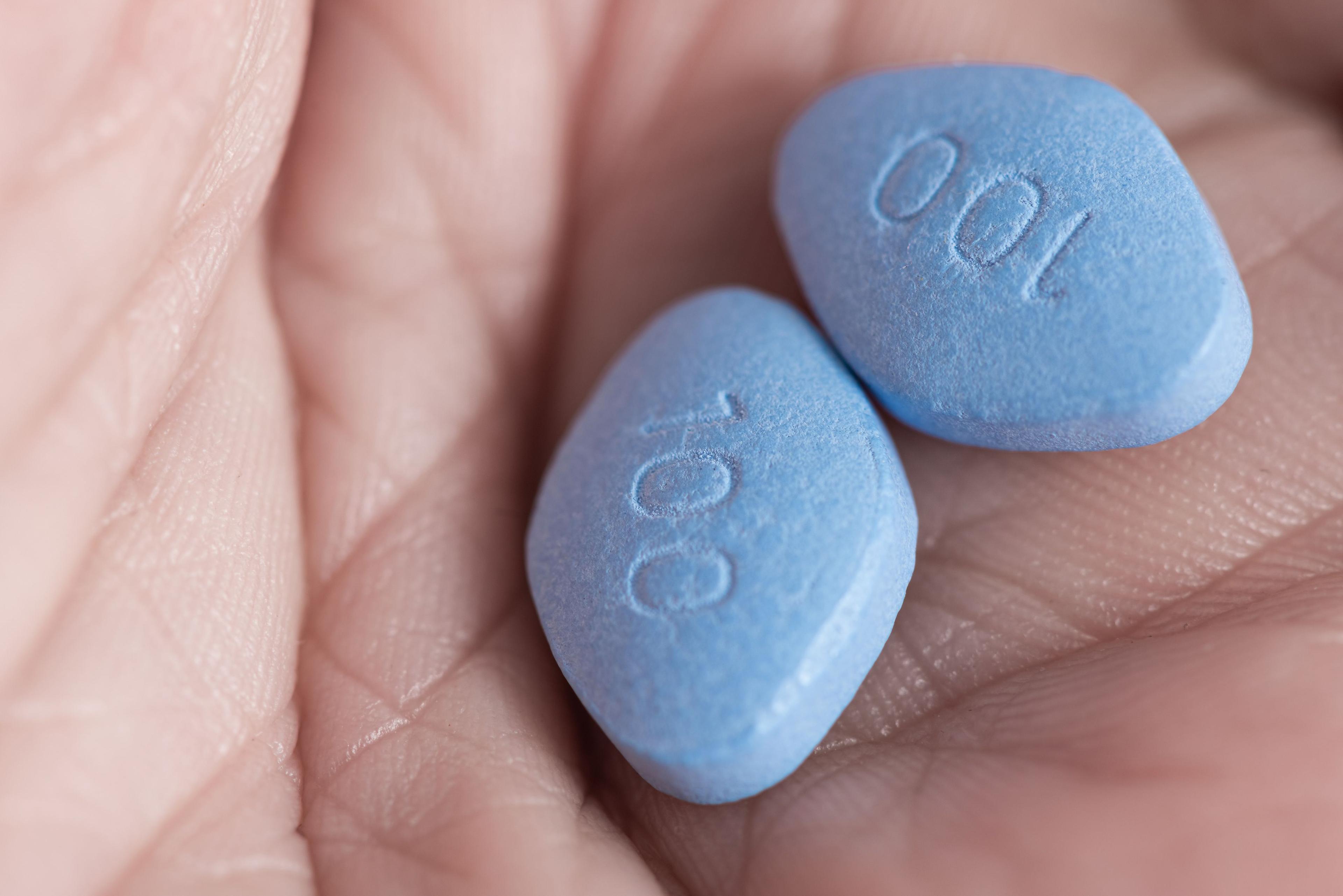 Two blue pills in a hand