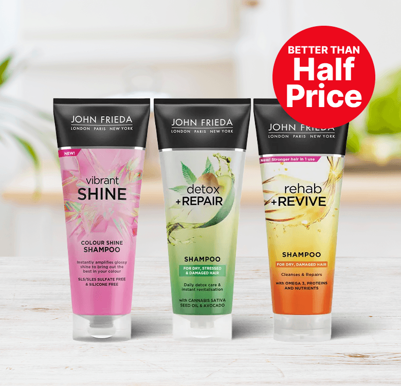 Three John Frieda shampoos: Vibrant Shine, Detox + Repair, and Rehab + Revive, displayed on a table with a "Better Than Half Price" tag.