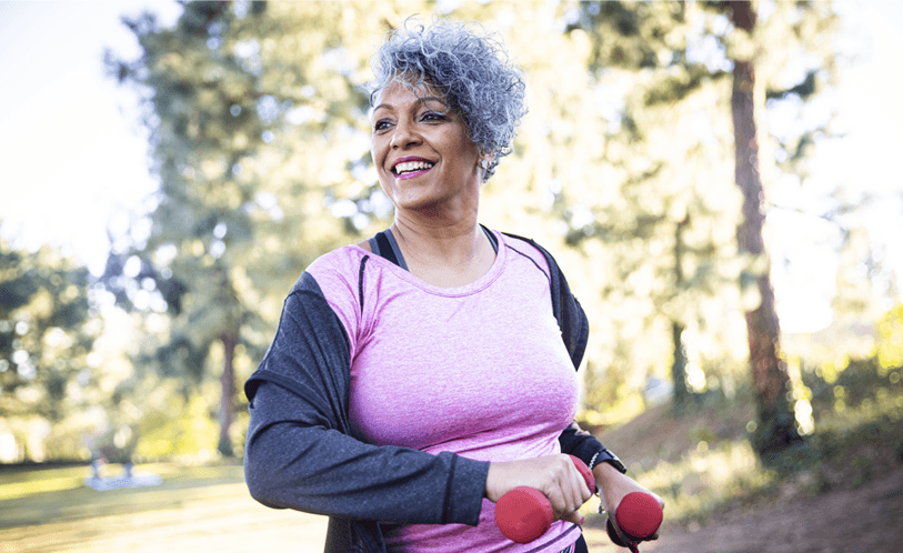 Woman smiling walking with hand weights in the park